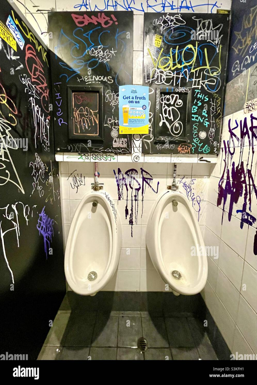 Graffiti and tags on wall and Urinals in public washroom Stock