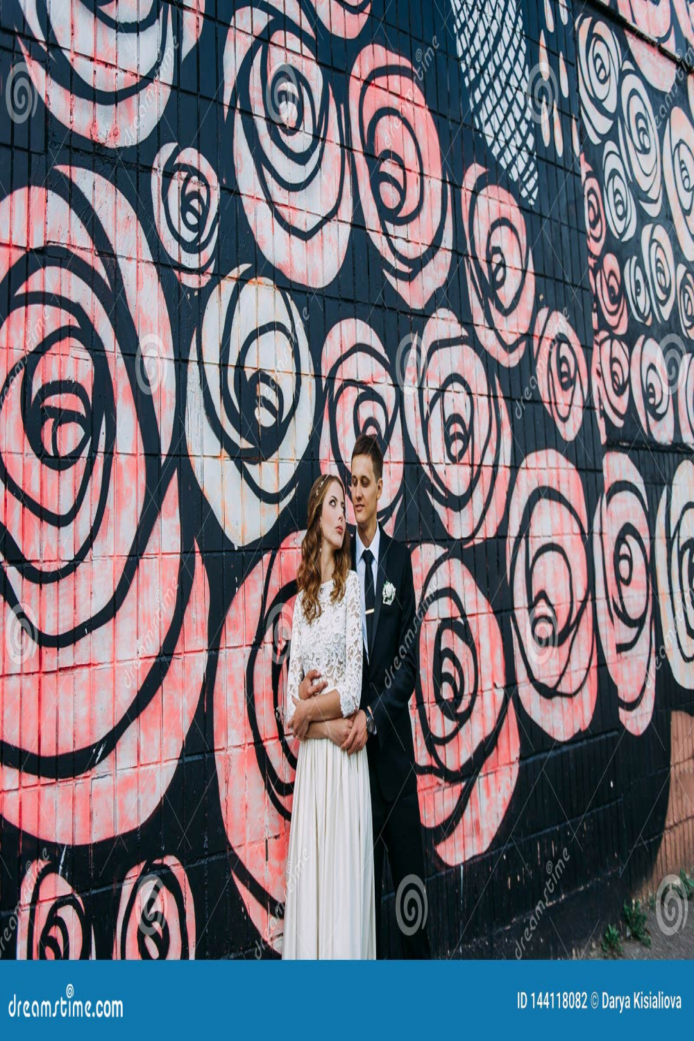 Newlyweds Embracing Next To Graffiti Wall