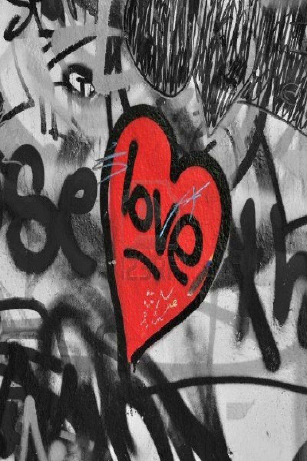 Red painted love heart on graffiti covered black and white wall