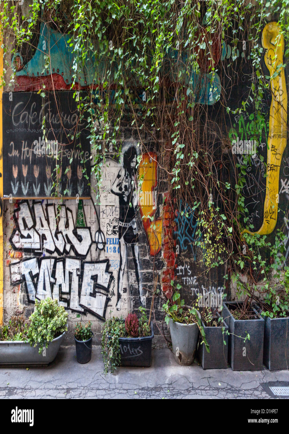 Wall with Graffiti, street art and plants outside the Cafe Cinema