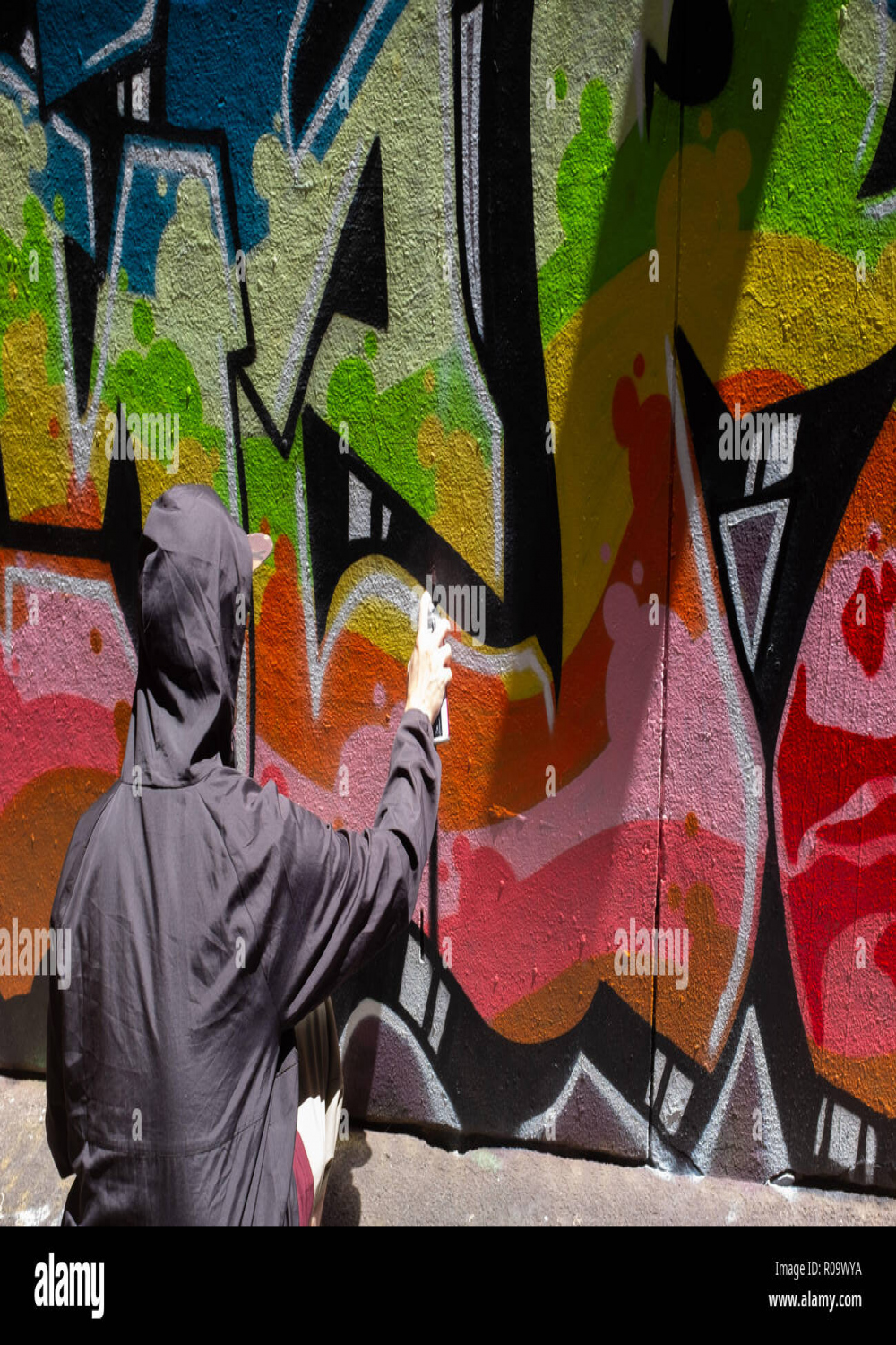 Man spraying graffiti wall in -Fotos und -Bildmaterial in hoher