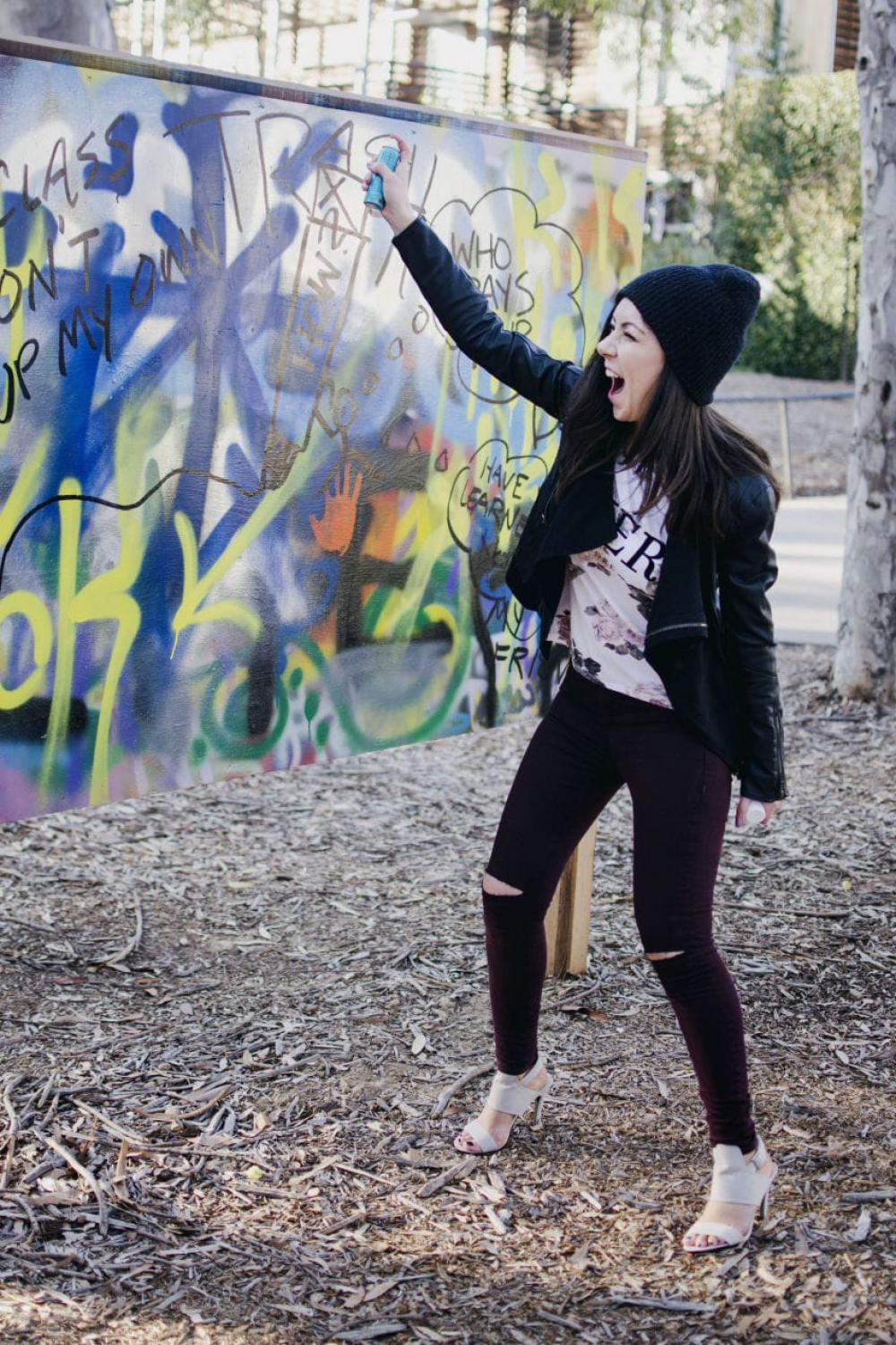 Model painting on a graffiti wall and showing her outfit - Style